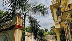 A courtyard with a marble floor, palm trees, and traditional architecture. - Krishna Palace - A Heritage Boutique Hotel (Jaipur)