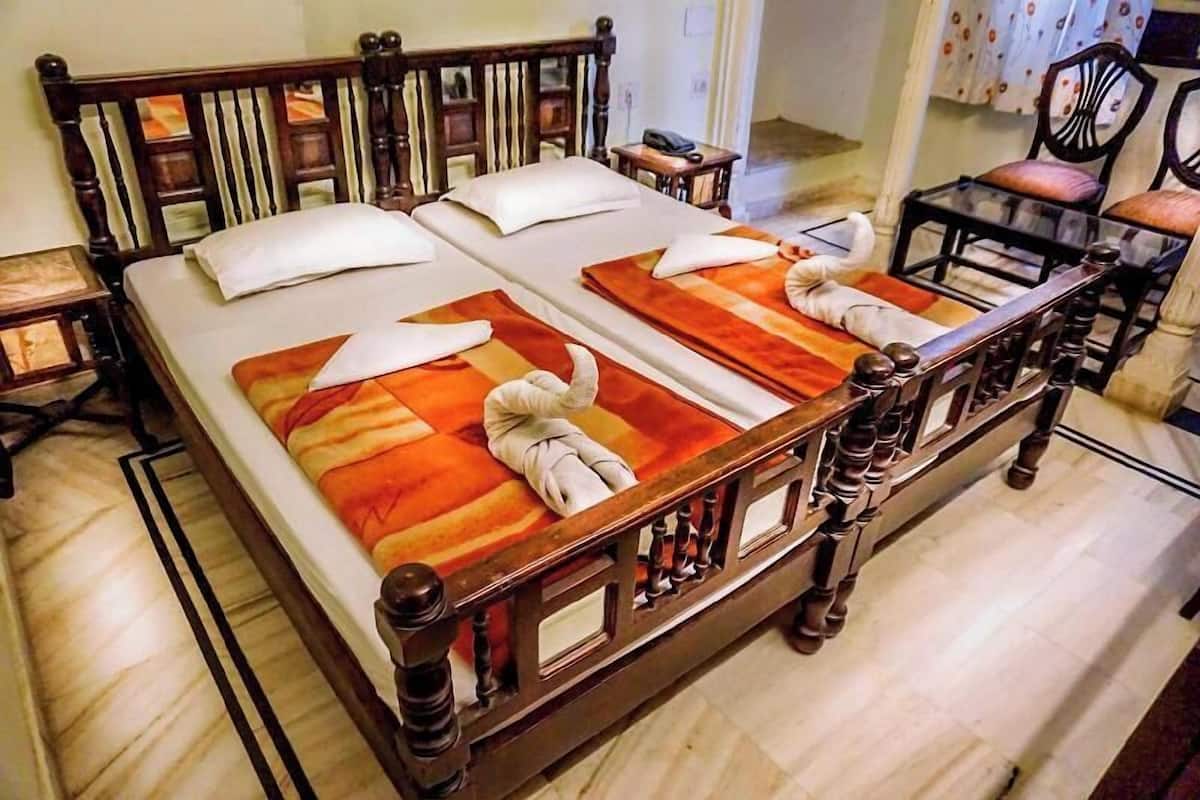 A double bed with a wooden headboard and footboard, two bedside tables, and a chair with a cushion.