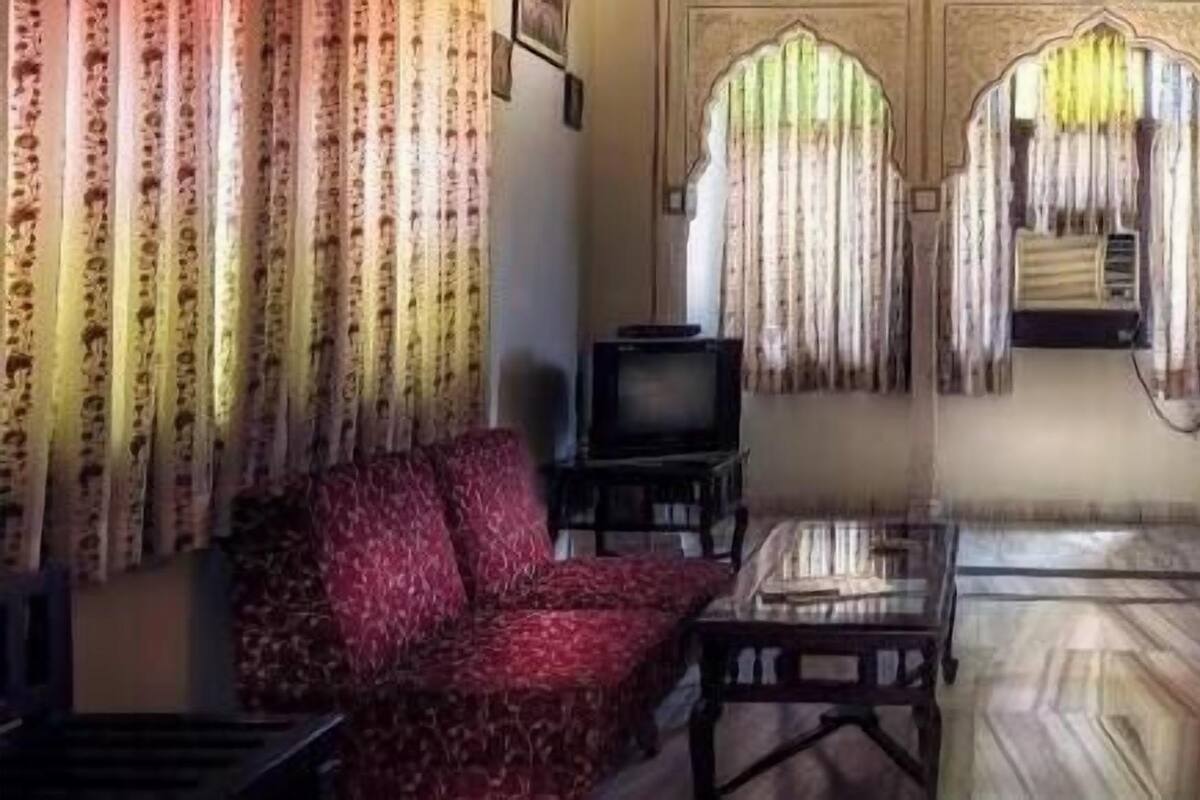 A traditional room with a bed, a desk, a chair, and curtains.