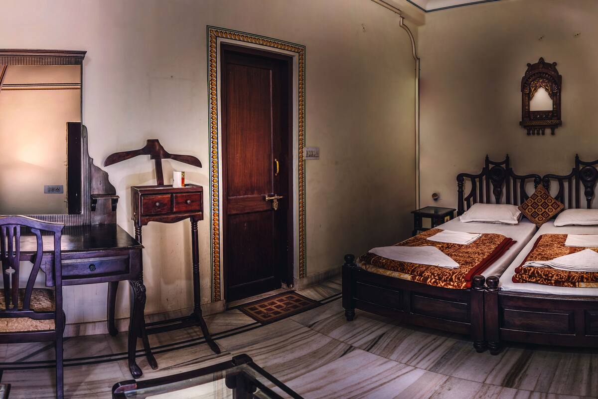 A room with a bed, a desk, a chair, and a door.