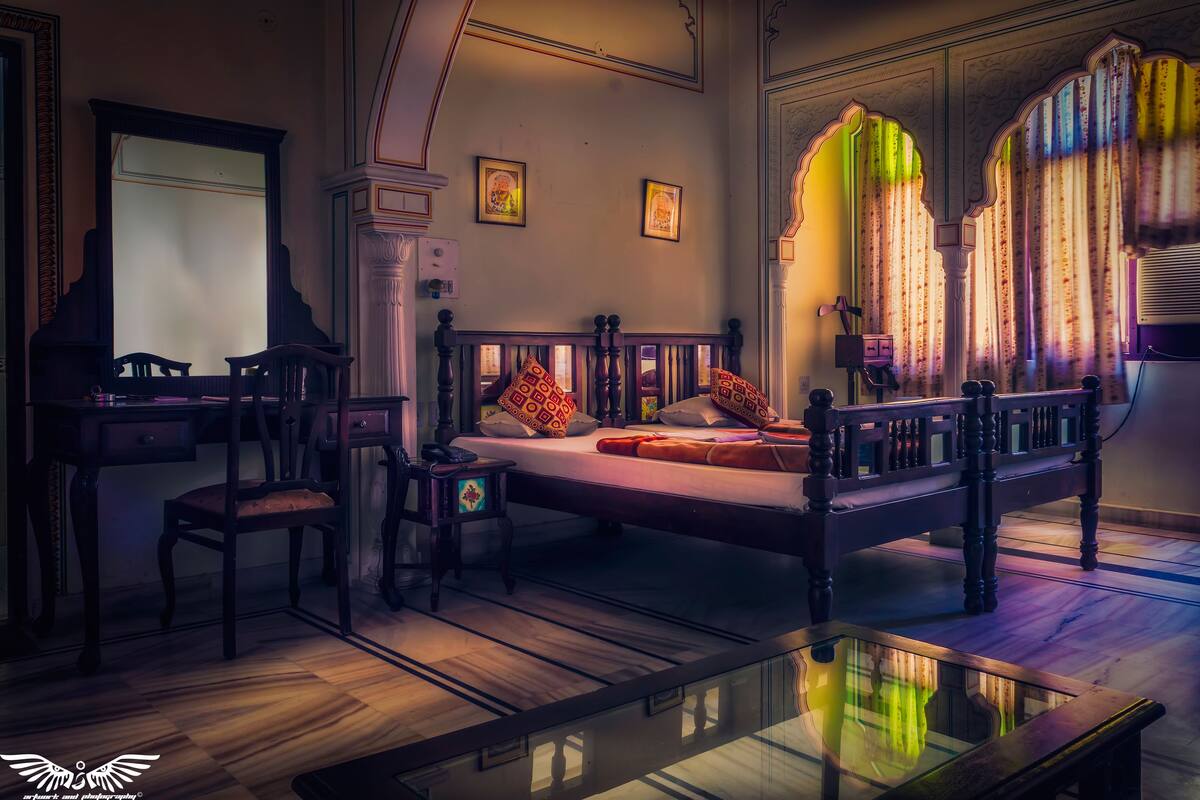 A room with a bed, a desk, a chair, and a small table.