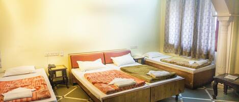 A hotel room with two single beds, a sofa bed, a small table, and a kettle.