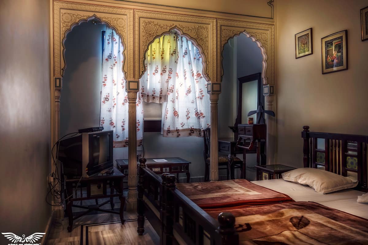A traditional room with a bed, a television, and a desk.
