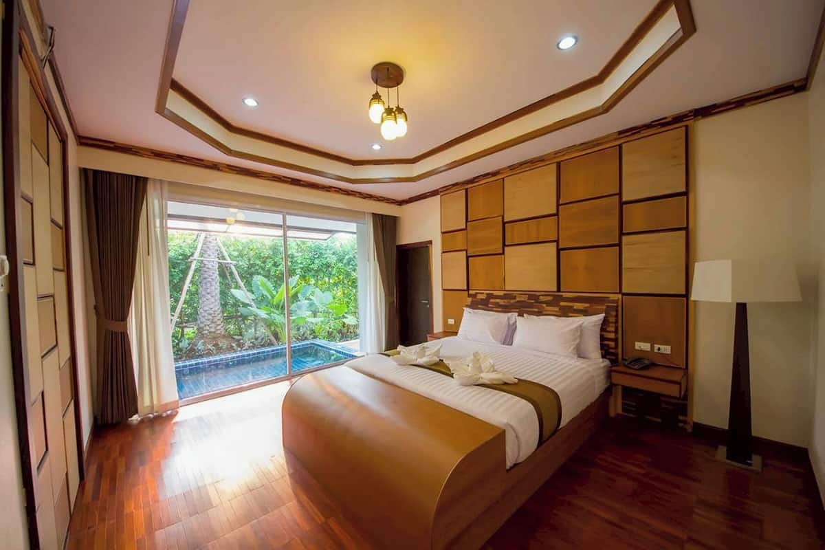 Un dormitorio amplio con una cama grande, un ventanal corredero que da a un balcón y vistas a zonas verdes.