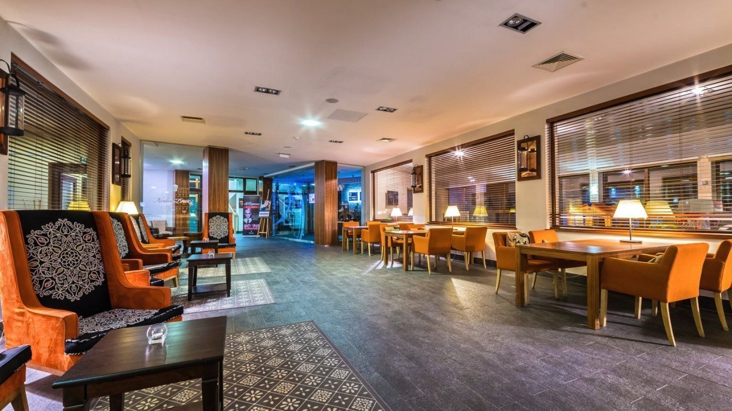 Um saguão de hotel com áreas de estar, balcão de recepção e vista para o restaurante.
