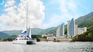 Un velero llamado 'Rosemary' sobre aguas abiertas, con un paisaje urbano al fondo, incluyendo un hotel destacado y varios edificios de gran altura.