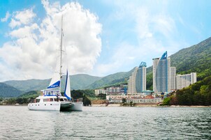 Un velero llamado 'Rosemary' sobre aguas abiertas, con un paisaje urbano al fondo, incluyendo un hotel destacado y varios edificios de gran altura.