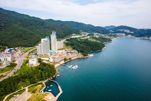 An aerial view of a coastal city with a marina, high-rise buildings, and a bridge connecting the mainland to an island.