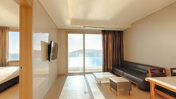 Una habitación de hotel moderna con cama, sofá, mesa de comedor y televisión.