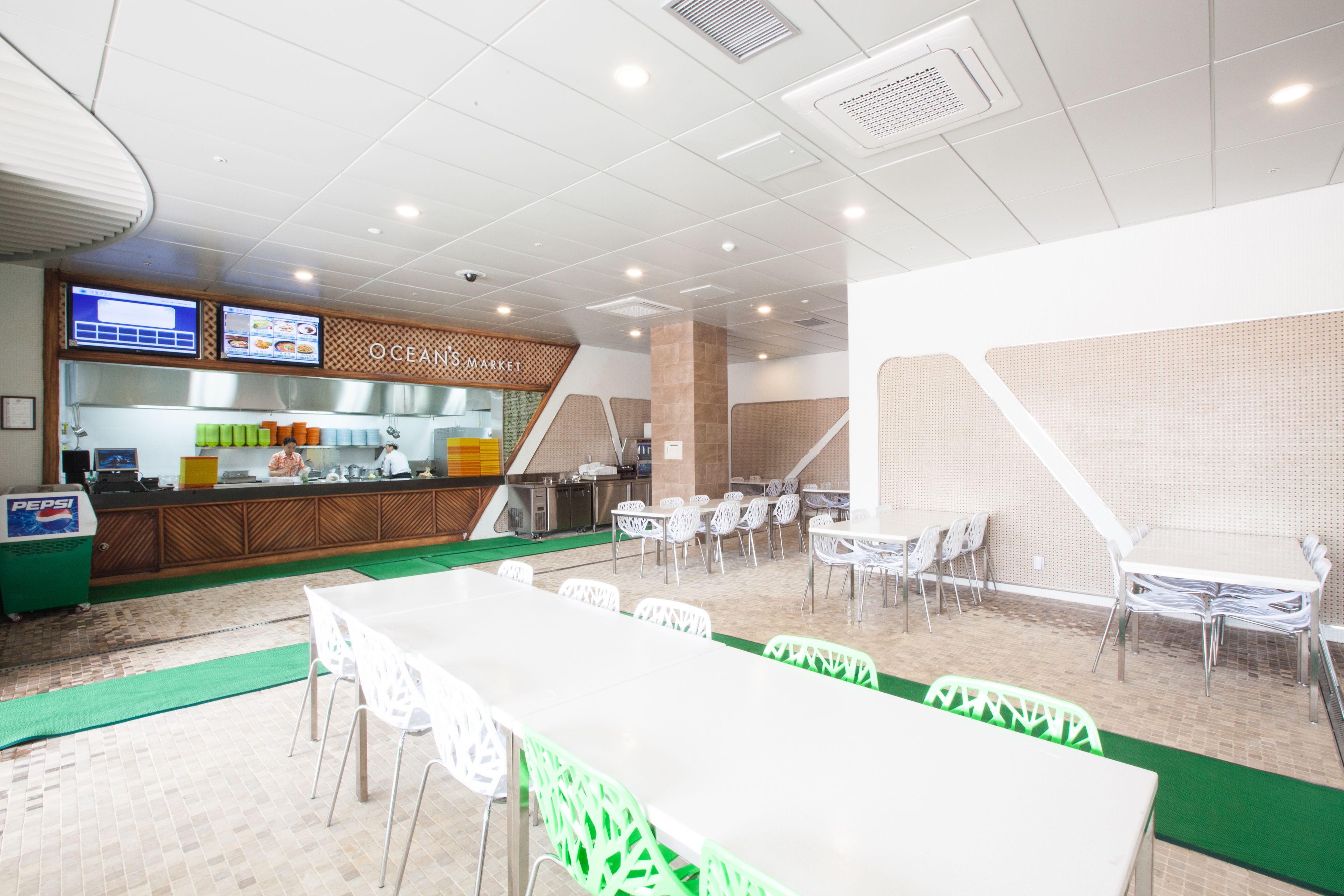 A restaurant with a counter, seating area, and a menu display.
