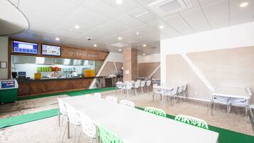 A restaurant with a counter, seating area, and a menu display.
