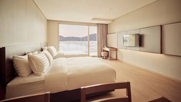Een moderne hotelkamer met een groot bed, een aan de muur bevestigde televisie en uitzicht op een waterpartij.