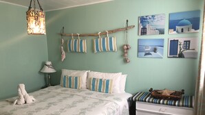 A bedroom with a bed, bedside table, lamp, and wall decorations including fish, pillows, and framed pictures. - The Rex Motel (Niagara Falls)