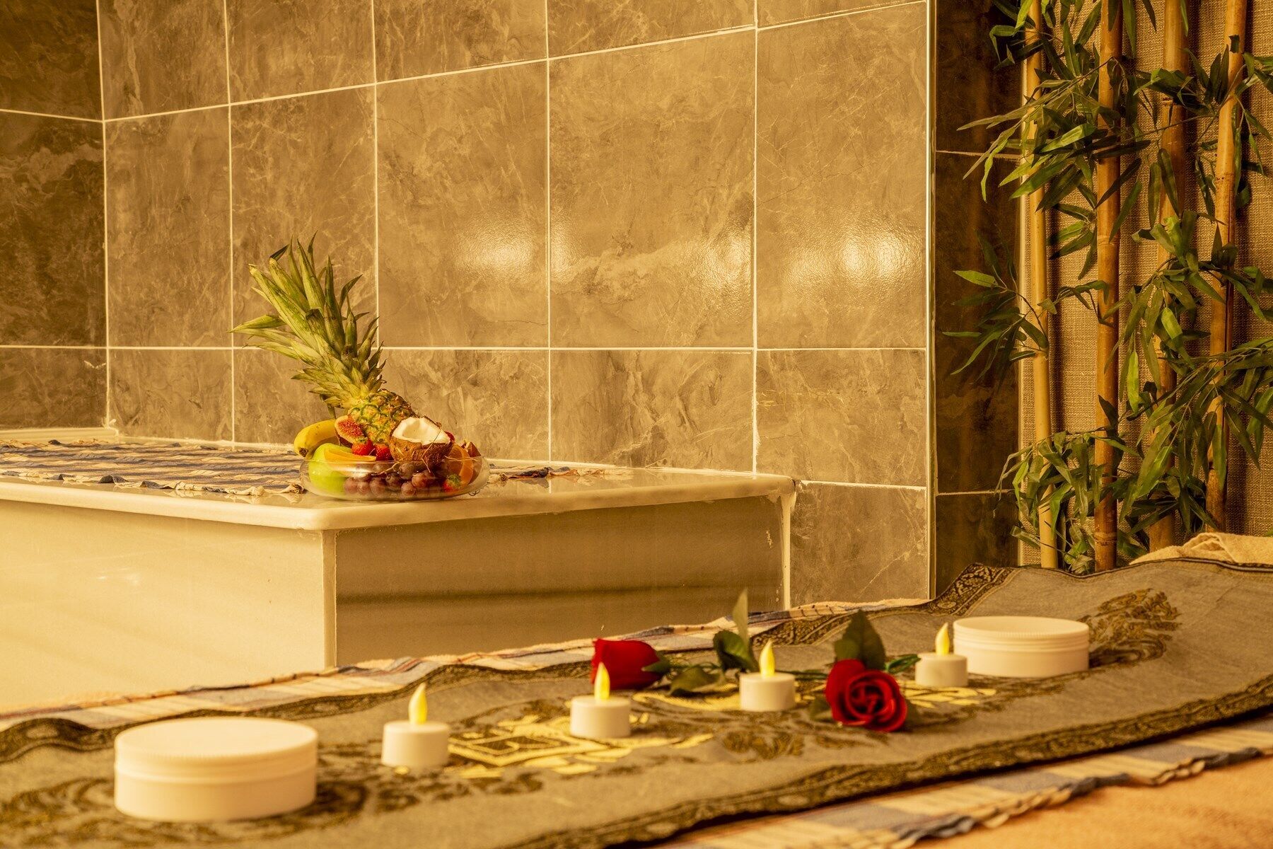 A bathroom with a bathtub, a fruit bowl, candles, and a decorative mat.