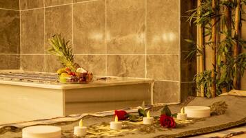 A bathroom with a bathtub, a fruit bowl, candles, and a decorative mat.