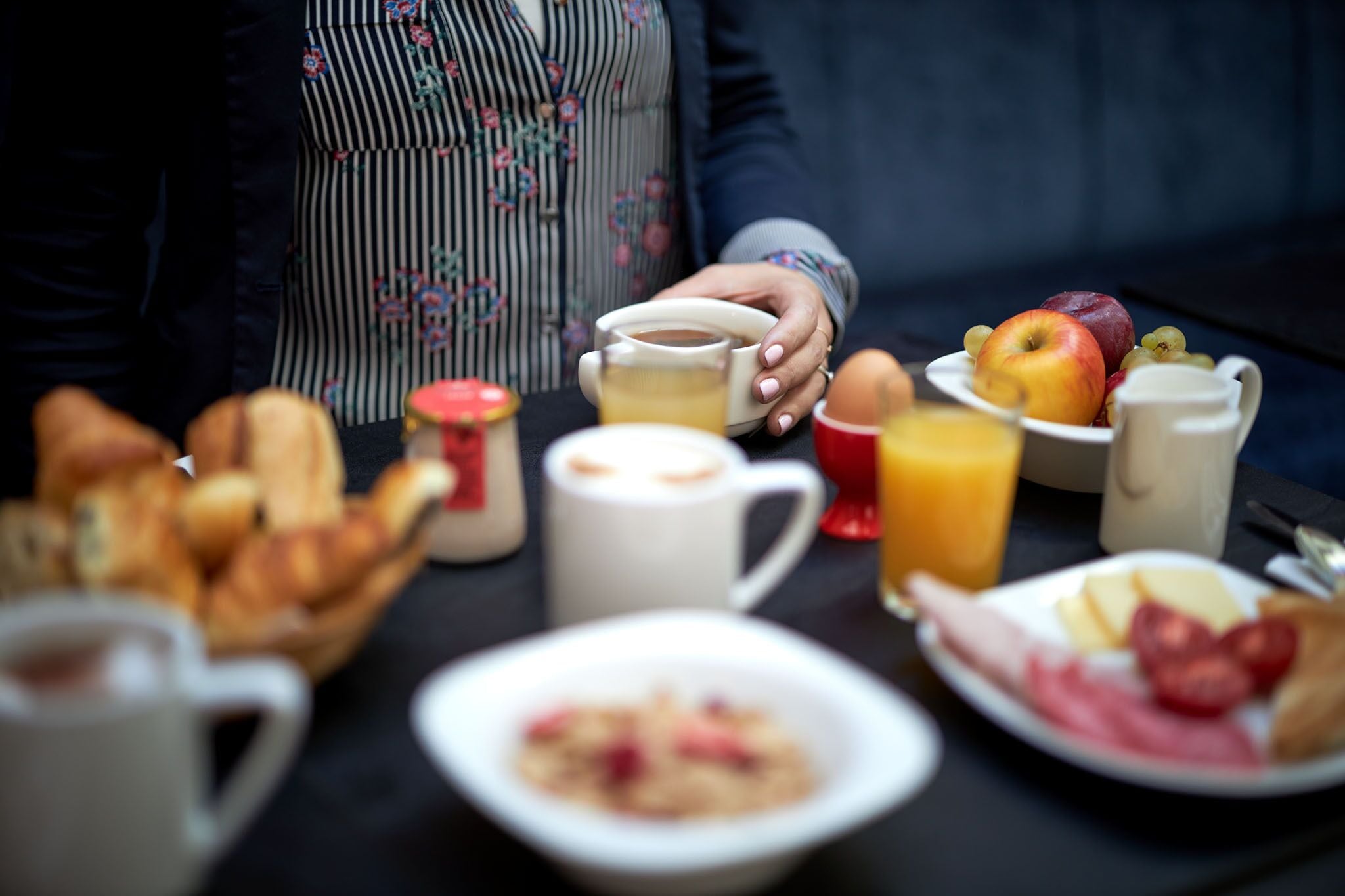 Una mesa de desayuno con diversos alimentos y bebidas, como pan, huevos, frutas y una taza de café.