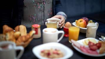 Una mesa de desayuno con diversos alimentos y bebidas, como pan, huevos, frutas y una taza de café.