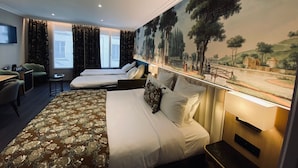 A hotel room with two single beds, a large bed with a floral bedspread, a desk with a chair, a small table, and a TV on the wall. - Hôtel Tourisme Avenue (Paris)
