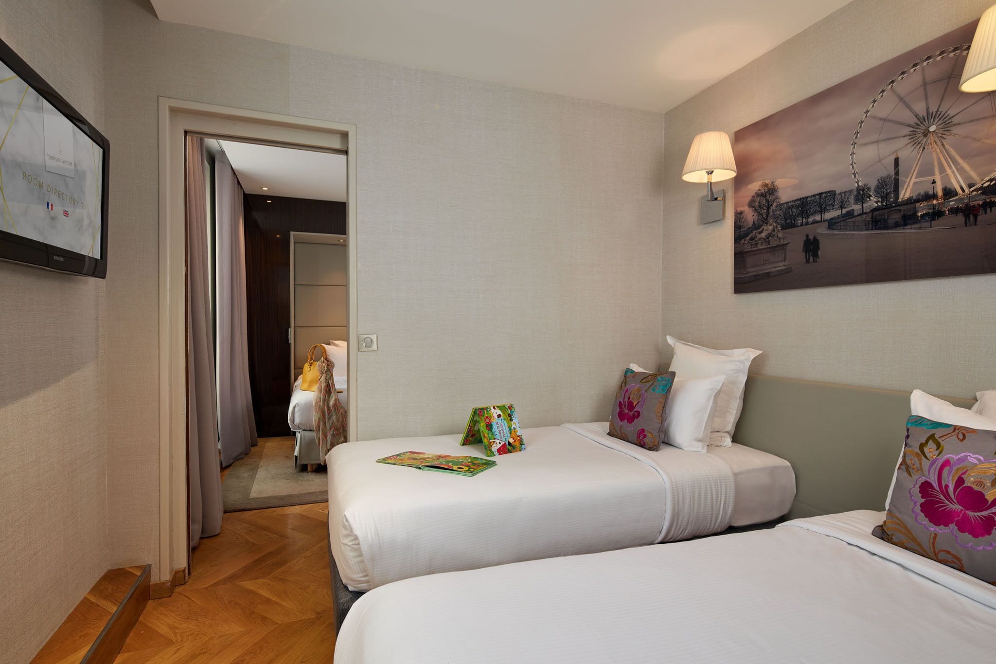 A hotel room with two beds, a painting of a Ferris wheel, and a map on the wall.