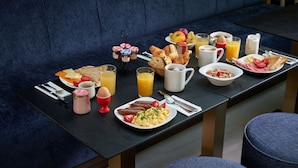 A breakfast buffet with various food items and beverages on a table in a restaurant. - Hôtel Tourisme Avenue (Paris)