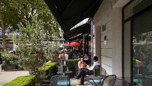 An outdoor seating area with tables and chairs, surrounded by greenery and a building facade. - Hôtel Tourisme Avenue (Paris)