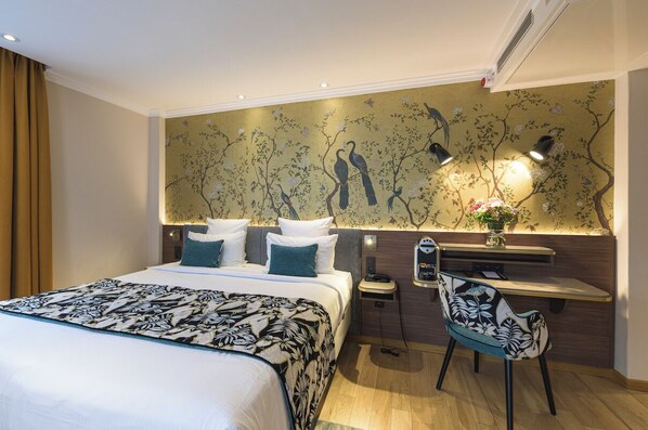 Una camera d'albergo con un letto grande, una scrivania con una sedia e un affresco floreale e con uccelli.