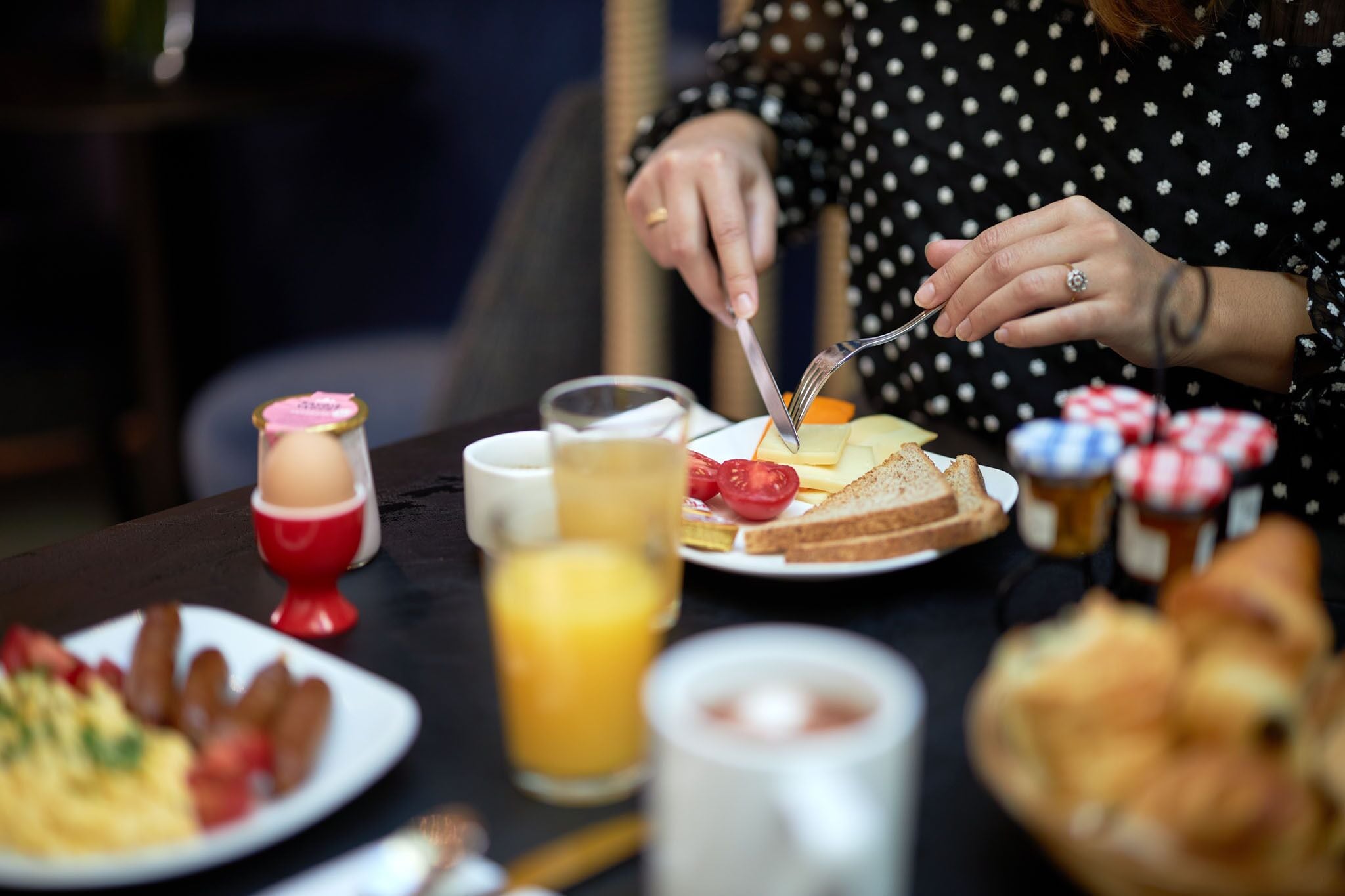 A breakfast setting with various food items and a person cutting toast.