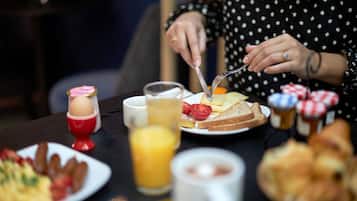 Ein Frühstückstisch mit verschiedenen Speisen und einer Person, die Toast schneidet.