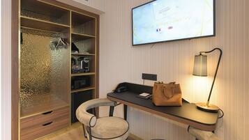 A hotel room with a large wardrobe, a desk with a lamp, and a television displaying a map.