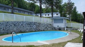 Una piscina con una pared de piedra y una valla blanca.