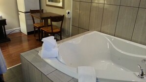 Un baño con una bañera grande, una mesita con sillas, un microondas y un teléfono.