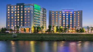 A hotel with multiple floors, a well-maintained lawn, and a body of water in the foreground.