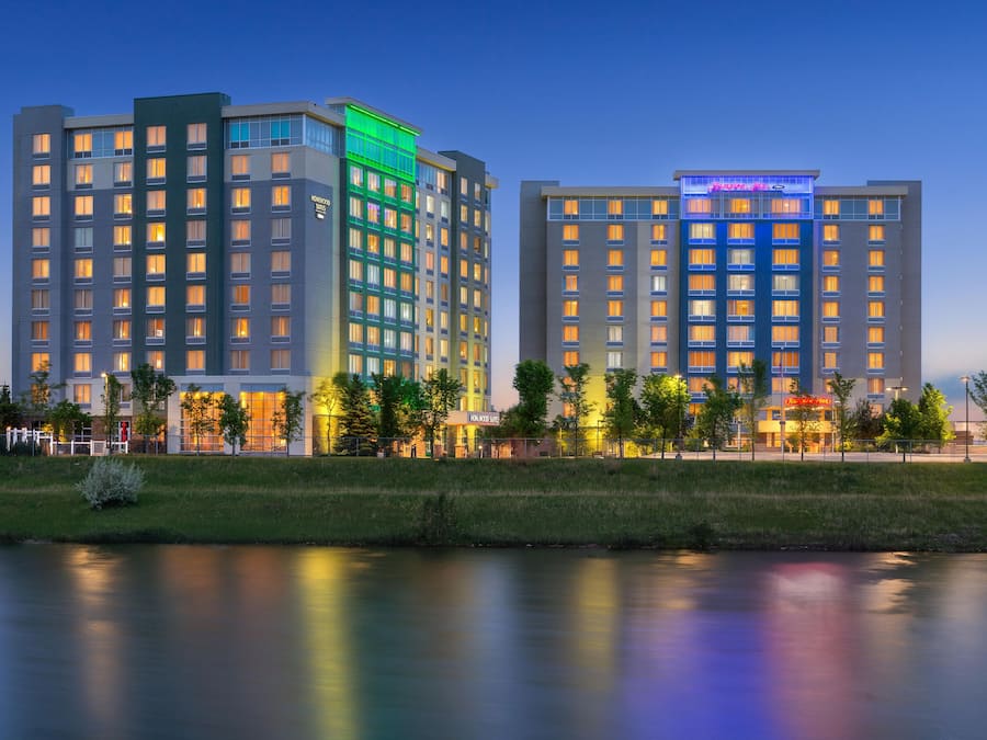 A hotel with multiple floors, a well-maintained lawn, and a body of water in the foreground.