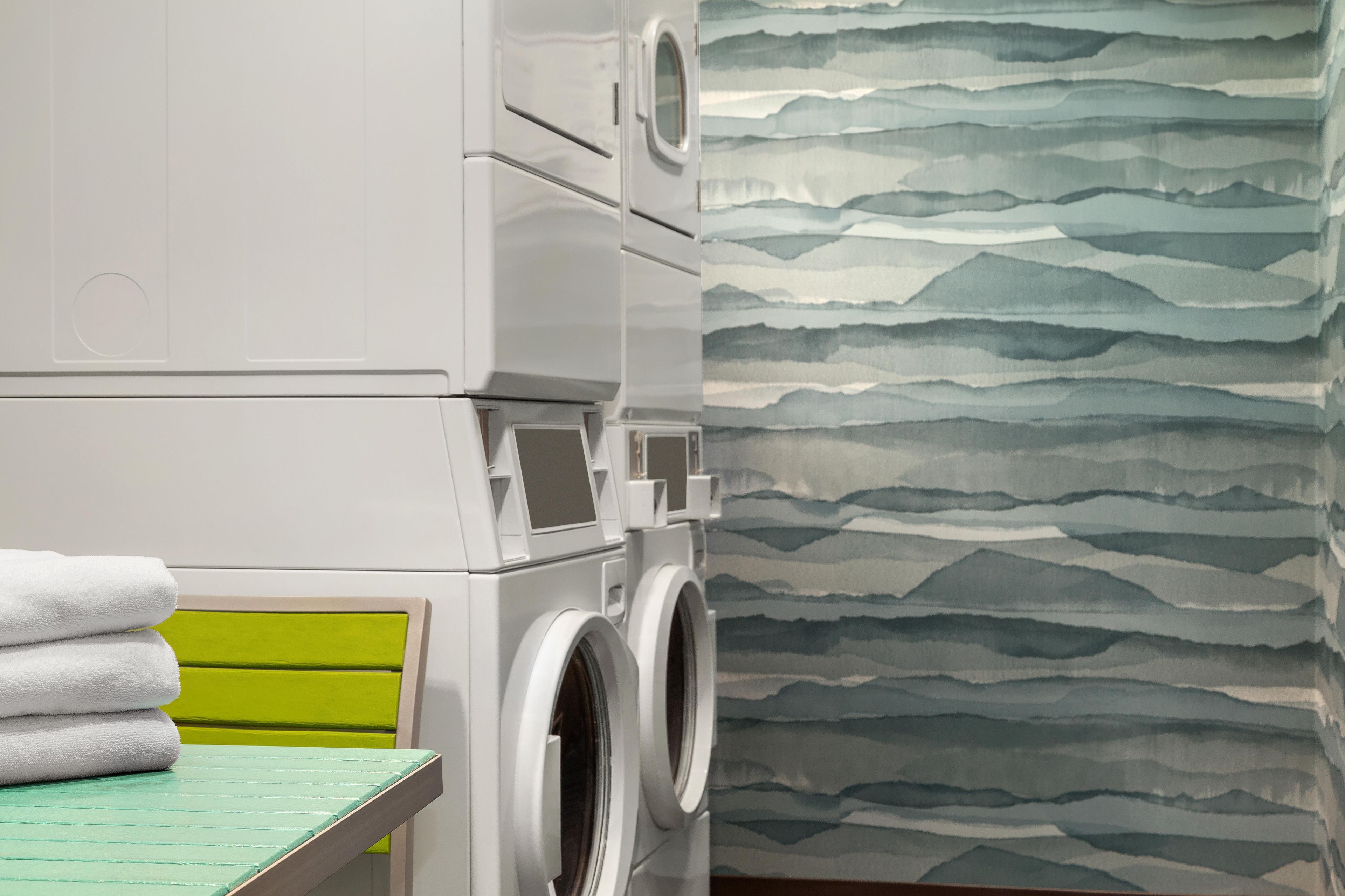 A laundry area with stacked washing machines and a table with folded towels.