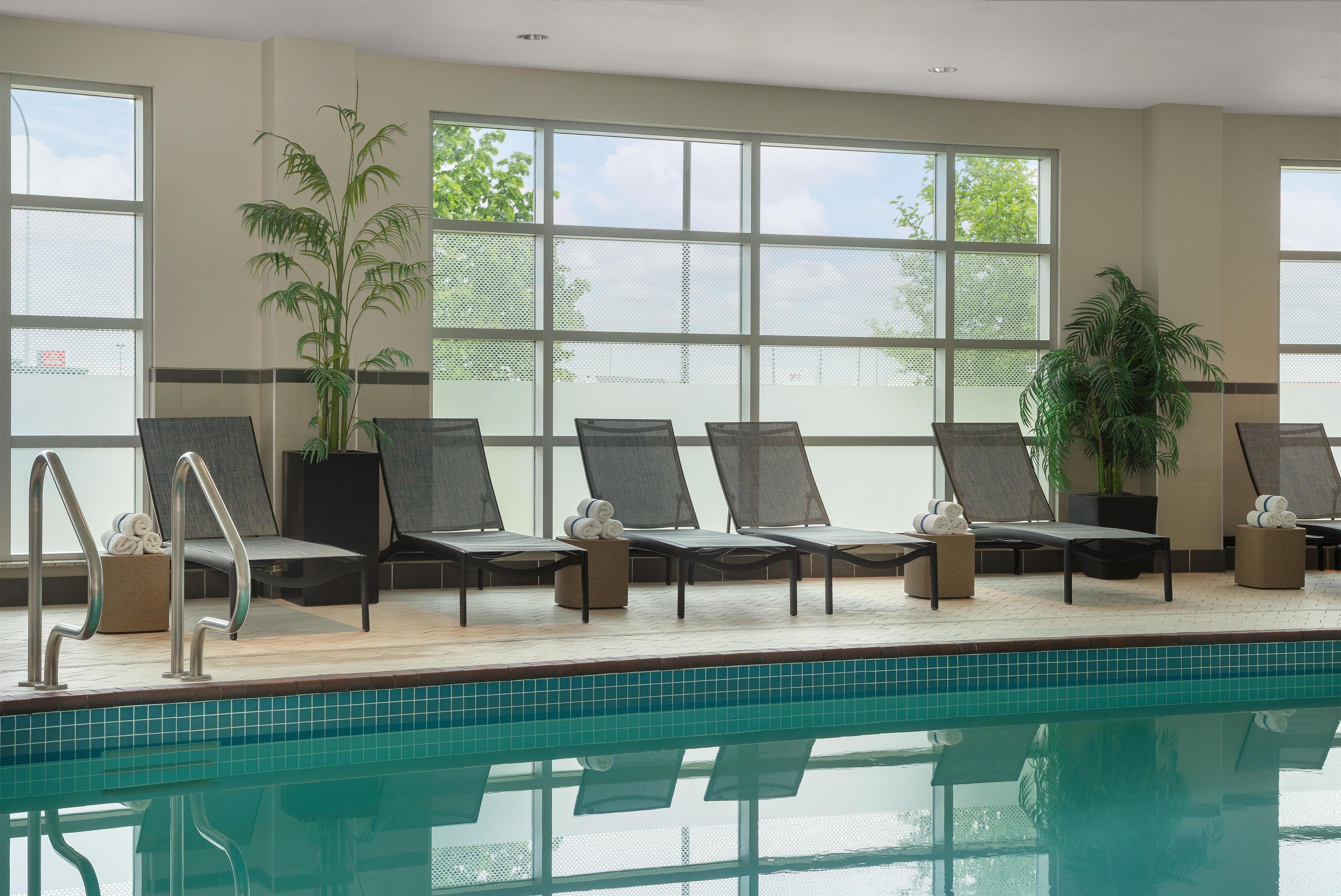 Zona junto a la piscina con sillones, piscina y ventanas amplias con vistas.