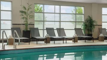 Zona junto a la piscina con sillones, piscina y ventanas amplias con vistas.
