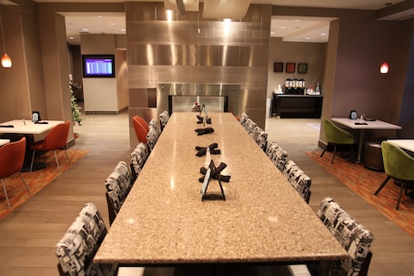 A conference room with a long table, chairs, a coffee station, and a TV screen.