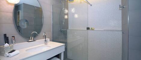 Un baño moderno con ducha de vidrio, un espejo grande y un tocador blanco.