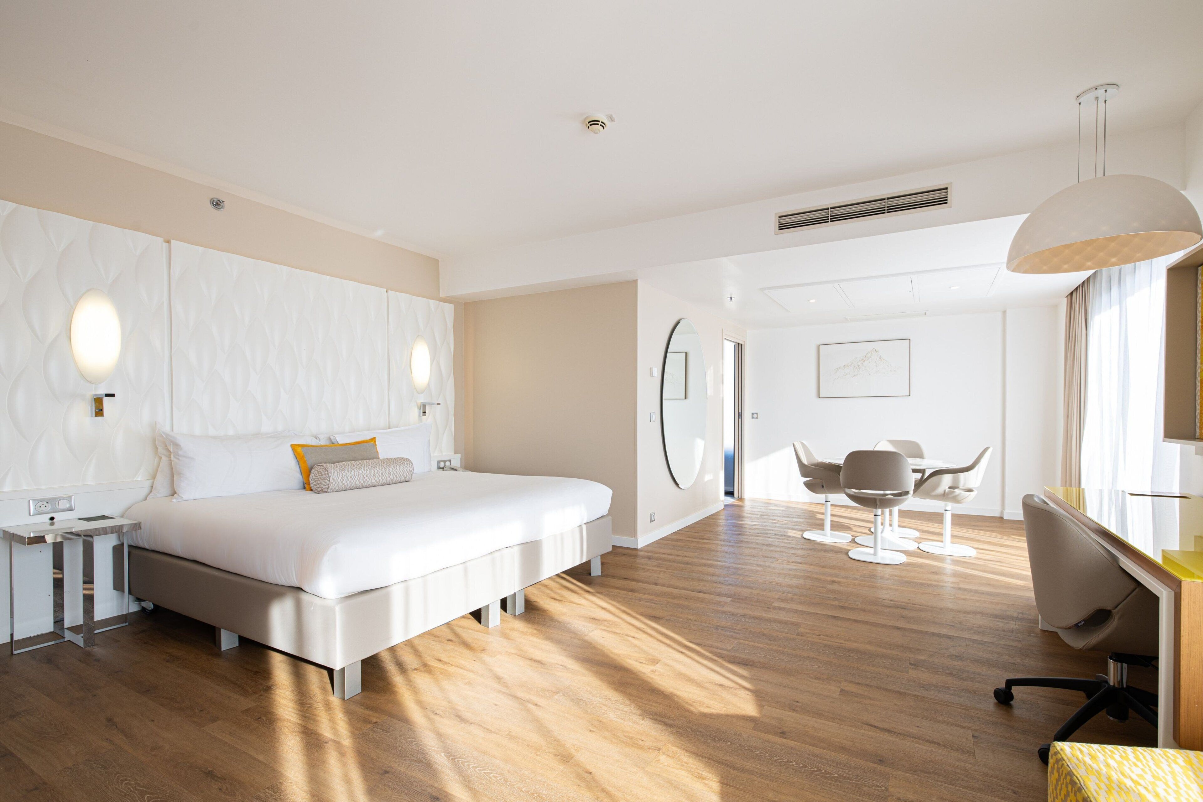 A modern hotel room with a large bed, bedside tables, a desk, and a chair.