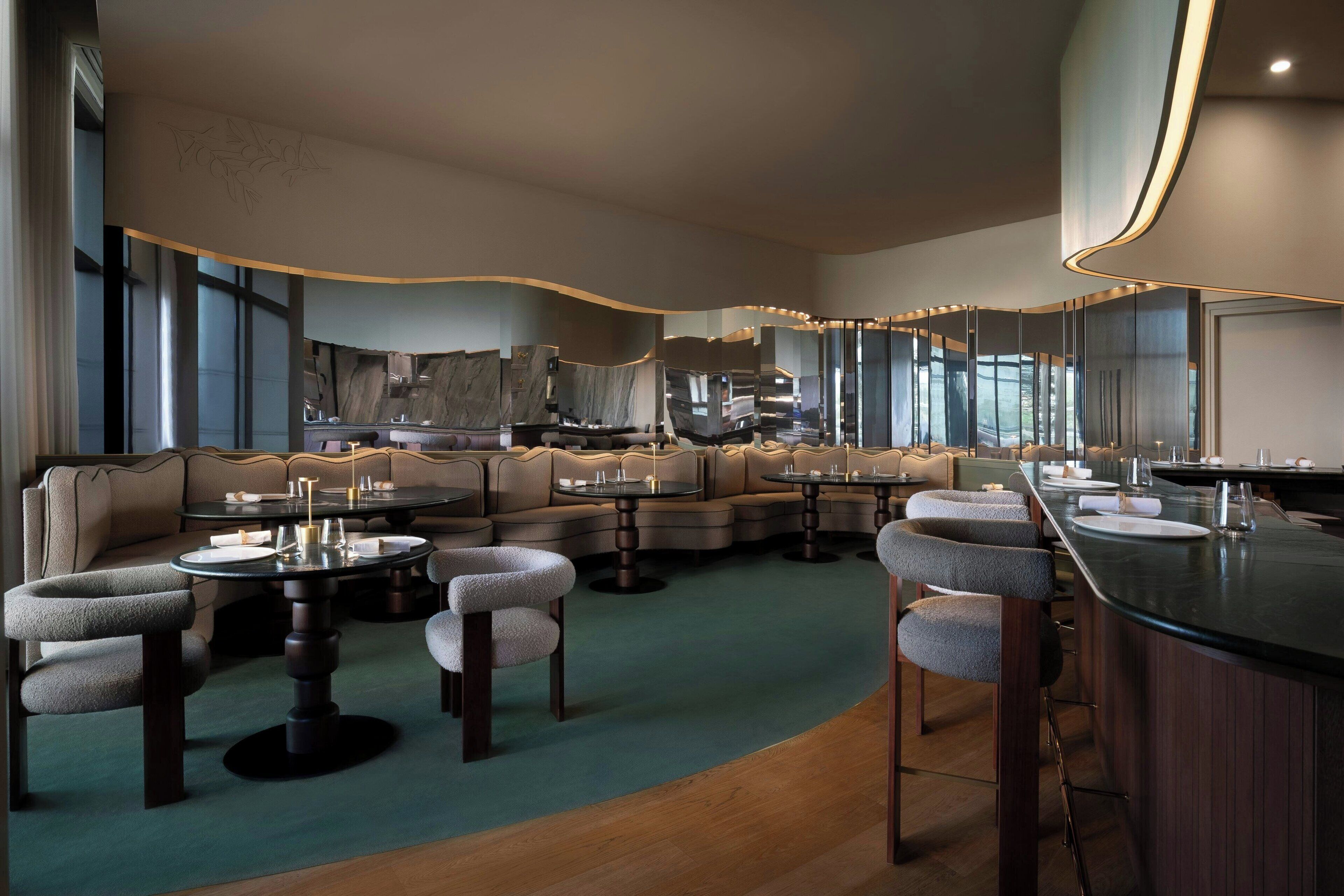 Un espace lounge moderne doté d’un plafond incurvé, de différents types de sièges et d’un comptoir de bar.