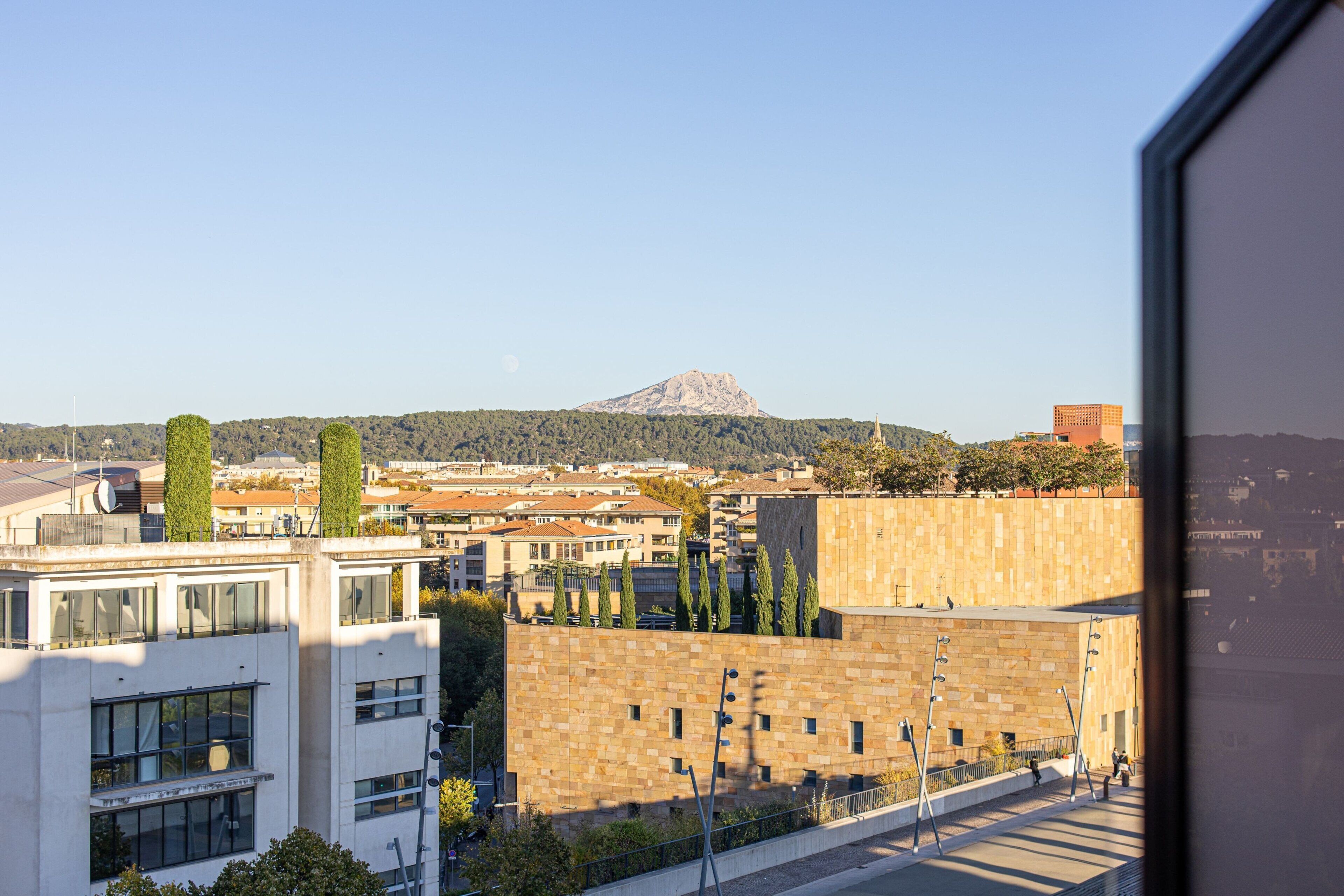 Un edificio moderno con vistas a una montaña y un paisaje urbano al fondo.