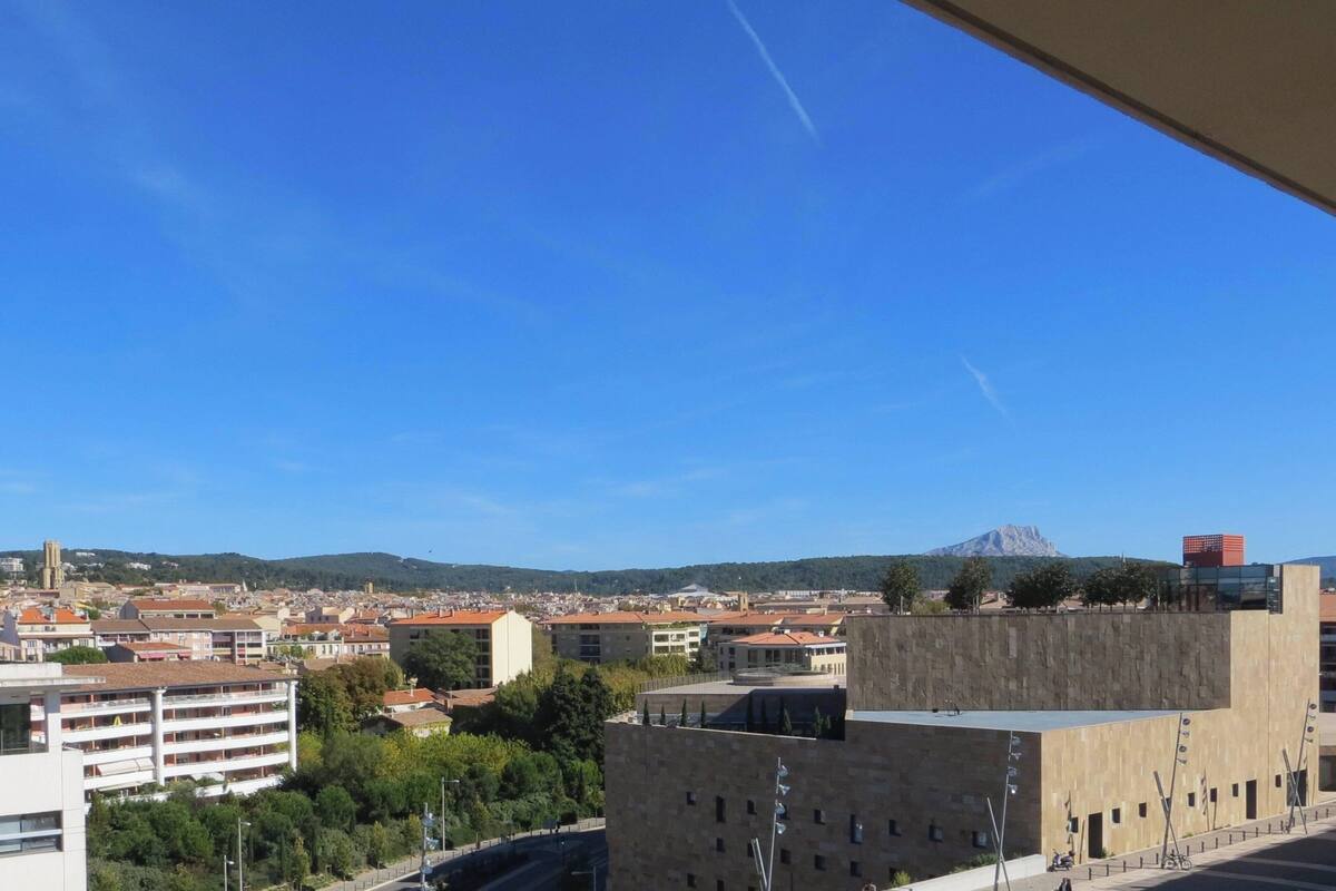A cityscape with a prominent building featuring a modern design and a view of a mountain in the distance.