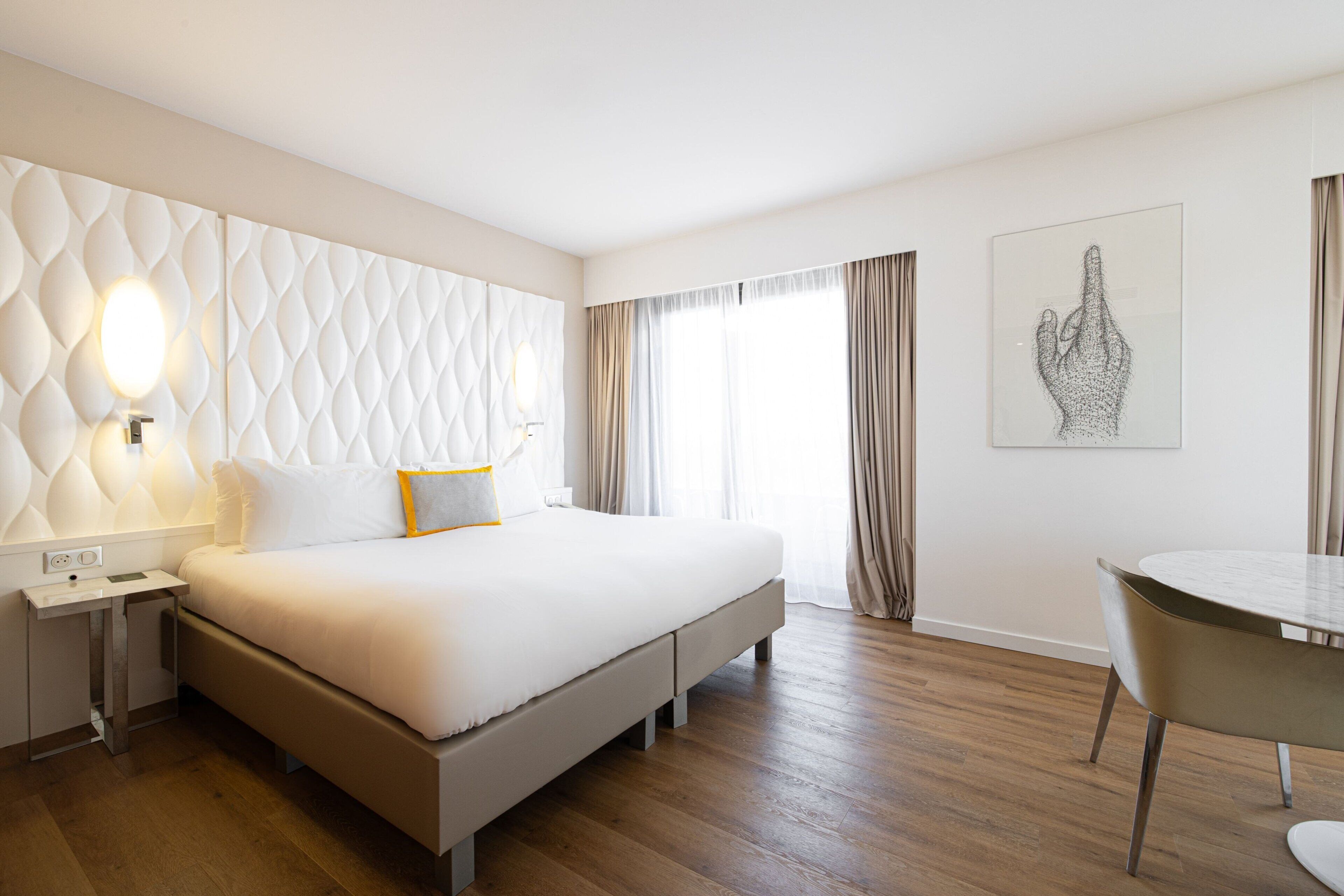 Una habitación de hotel moderna con una cama grande, una mesita de noche y un área de comedor.
