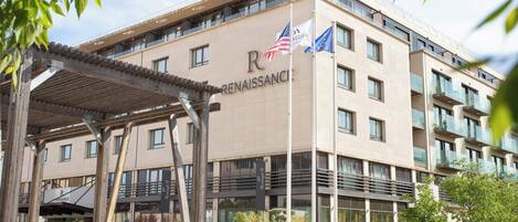 A modern hotel with a prominent 'Renaissance' sign, featuring a covered outdoor seating area and a bike parked nearby.