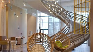 A modern interior with hanging chairs, a spiral staircase, and a dining area. - Renaissance Aix-en-Provence Hotel (Aix-en-Provence)