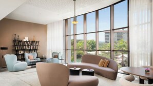 A modern living room with a large window, a round coffee table, and a sofa. - Renaissance Aix-en-Provence Hotel (Aix-en-Provence)
