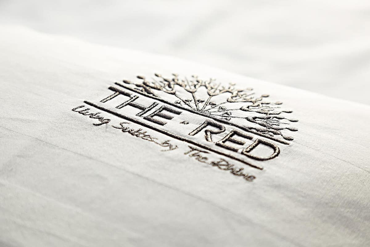 Un logo comprenant le texte « THE RED » et un motif d’arbre, indiquant le nom d’une marque ou d’une entreprise.
