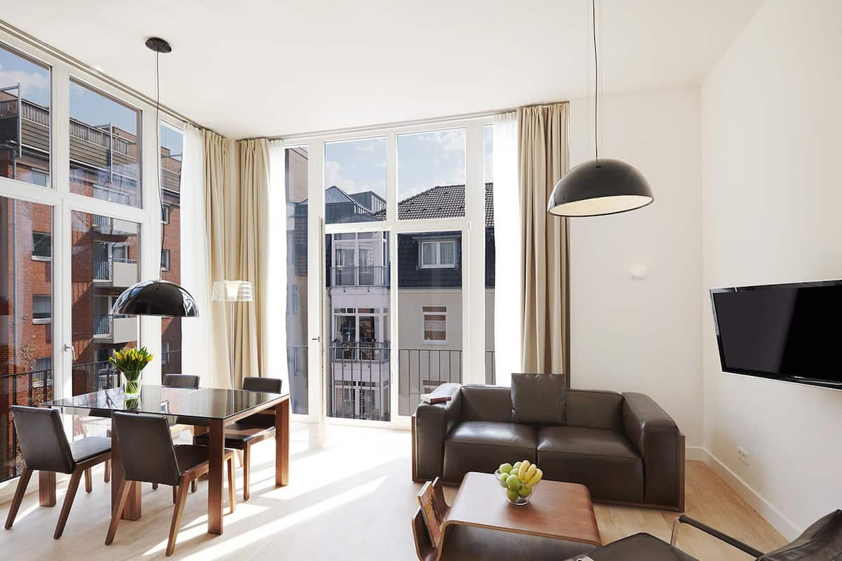 Un salon moderne comprenant un coin repas, un canapé, une table basse et un téléviseur fixé au mur.