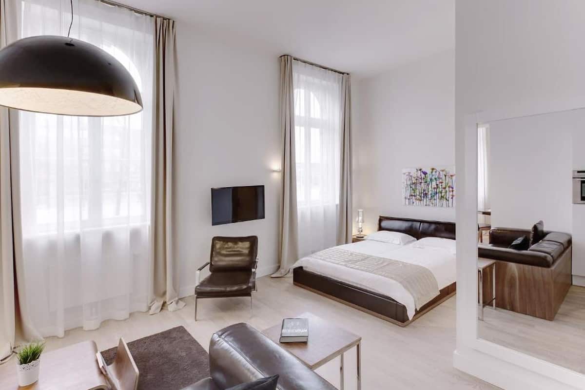Une chambre d’hôtel moderne avec un grand lit, un canapé, un bureau et une télévision.