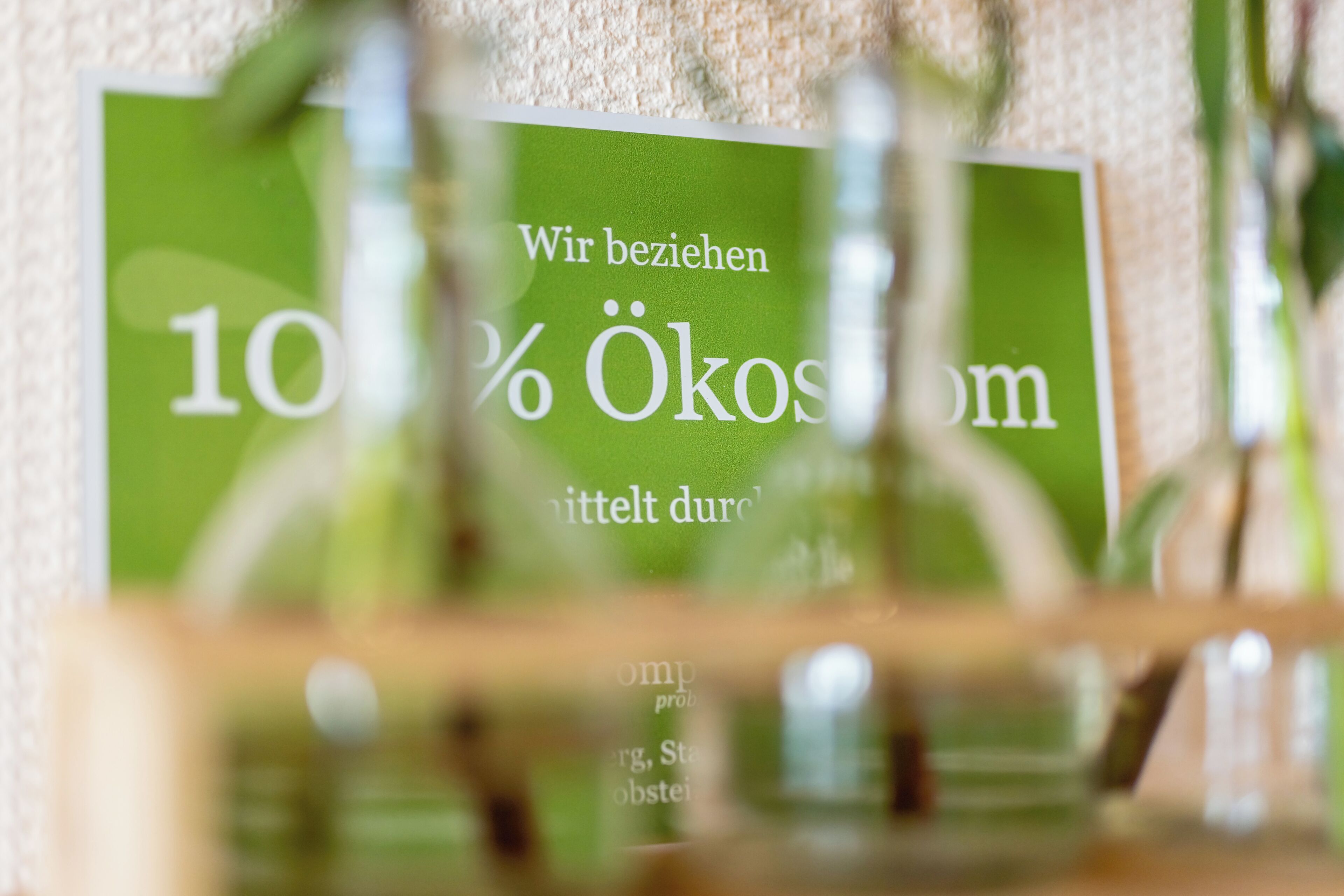 Een close-up van een groen bord met witte tekst, deels verborgen door een wazig object op de voorgrond.